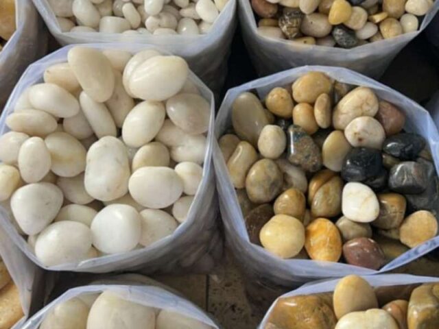 أكياس زلط نهري ملوّن بدرجات العنبري والبني والأسود بجانب زلط أبيض بيضاوي