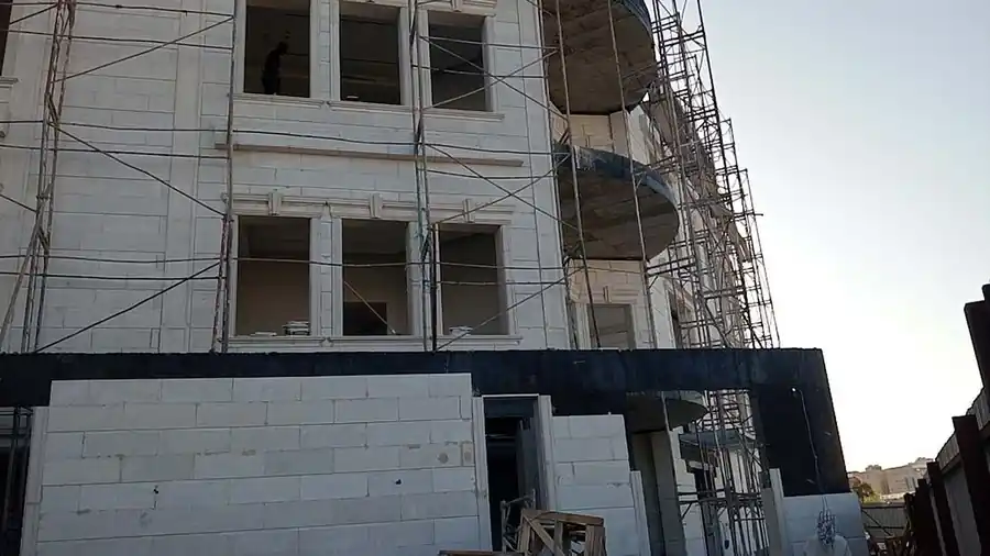 إطارات نوافذ مزخرفة وشرفة منحنية منفّذة بحجر الرياض الأبيض النسّاح في عمارة سكنية بجدة